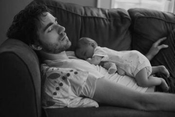 Father sleeping with baby in his arms